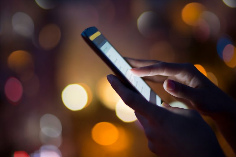 Woman using her mobile phone , city skyline night light  backgro