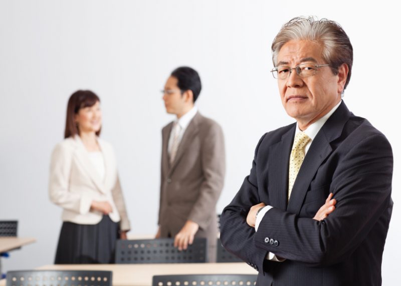 Businessman standing with arms crossed and colleagues in the background