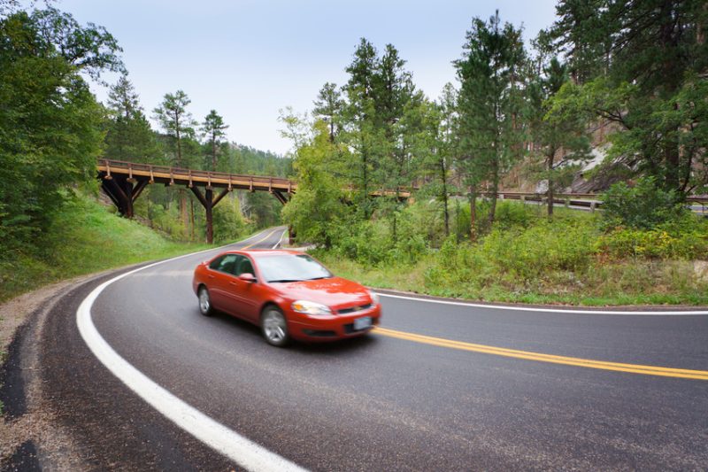 Red Sedan Car Driving Scenic Mountain Highway with Pigtail Bridge