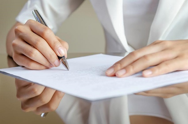 close-up of woman’s hands signing a contract