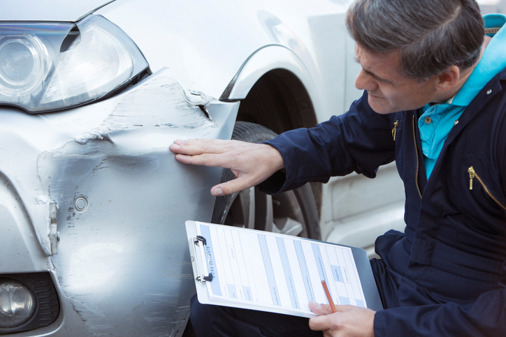 Auto Workshop Mechanic Inspecting Damage To Car